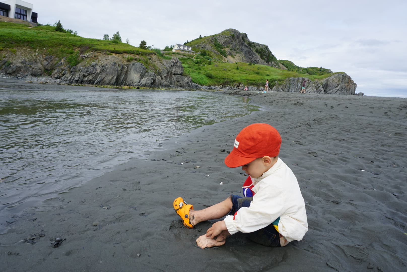 Baby O sitting in the sand in Salmon Cove